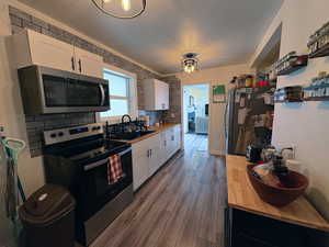 Kitchen featuring stainless steel appliances, white cabinets, tasteful backsplash, and dark wood finished floors