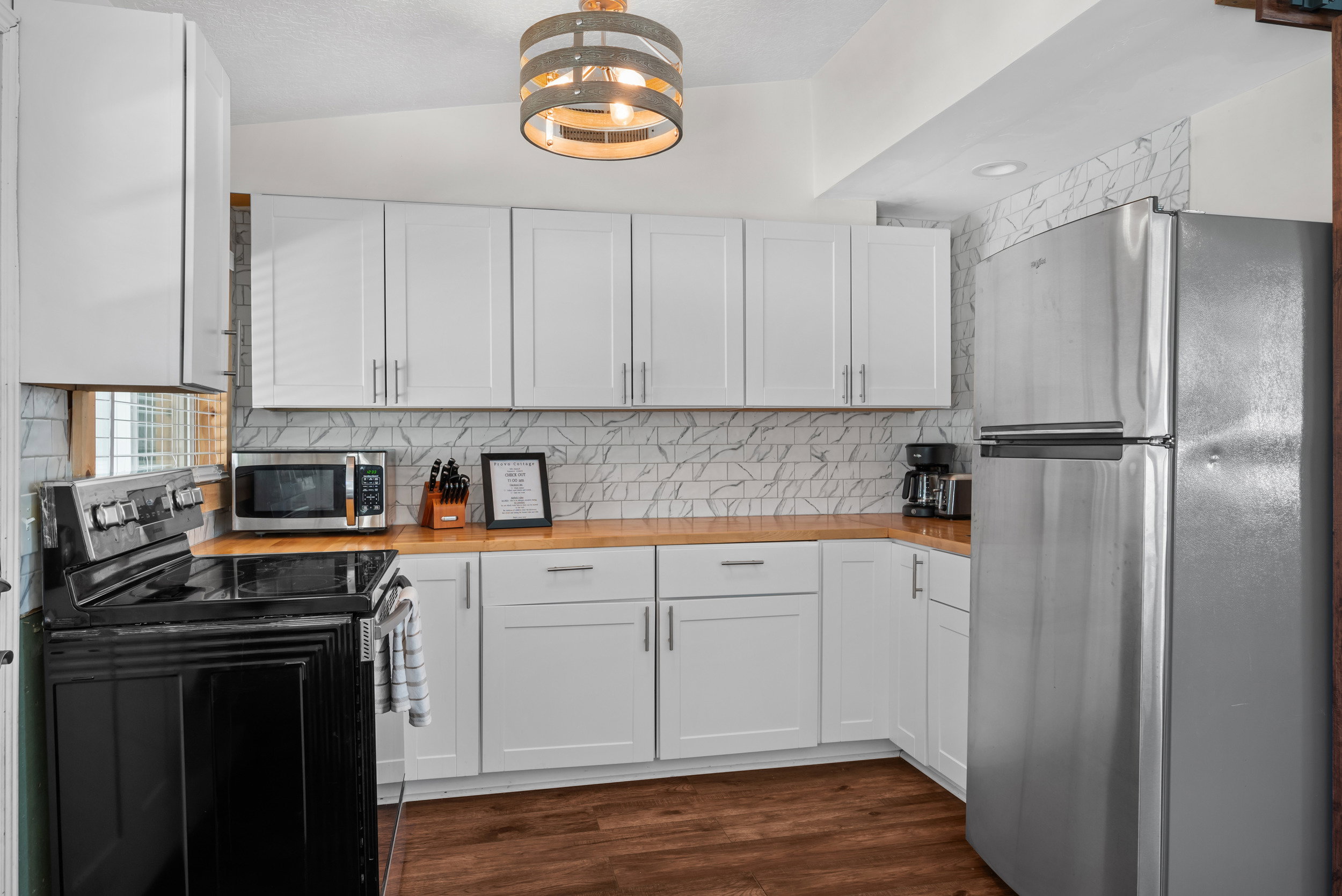 Kitchen featuring white shaker-style cabinetry, wood-finish countertops, stainless steel appliances, and a patterned tile backsplash
