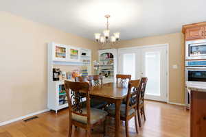 Dining room featuring suspended lighting, light wood-type flooring, and french doors