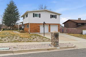 View of front facade with brick siding, driveway, and a garage