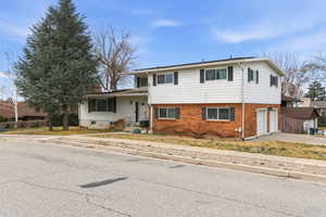 Tri-level home with brick siding, a garage, and concrete driveway