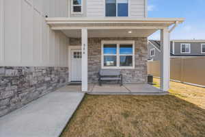 Property entrance featuring covered porch, stone siding, and board and batten siding