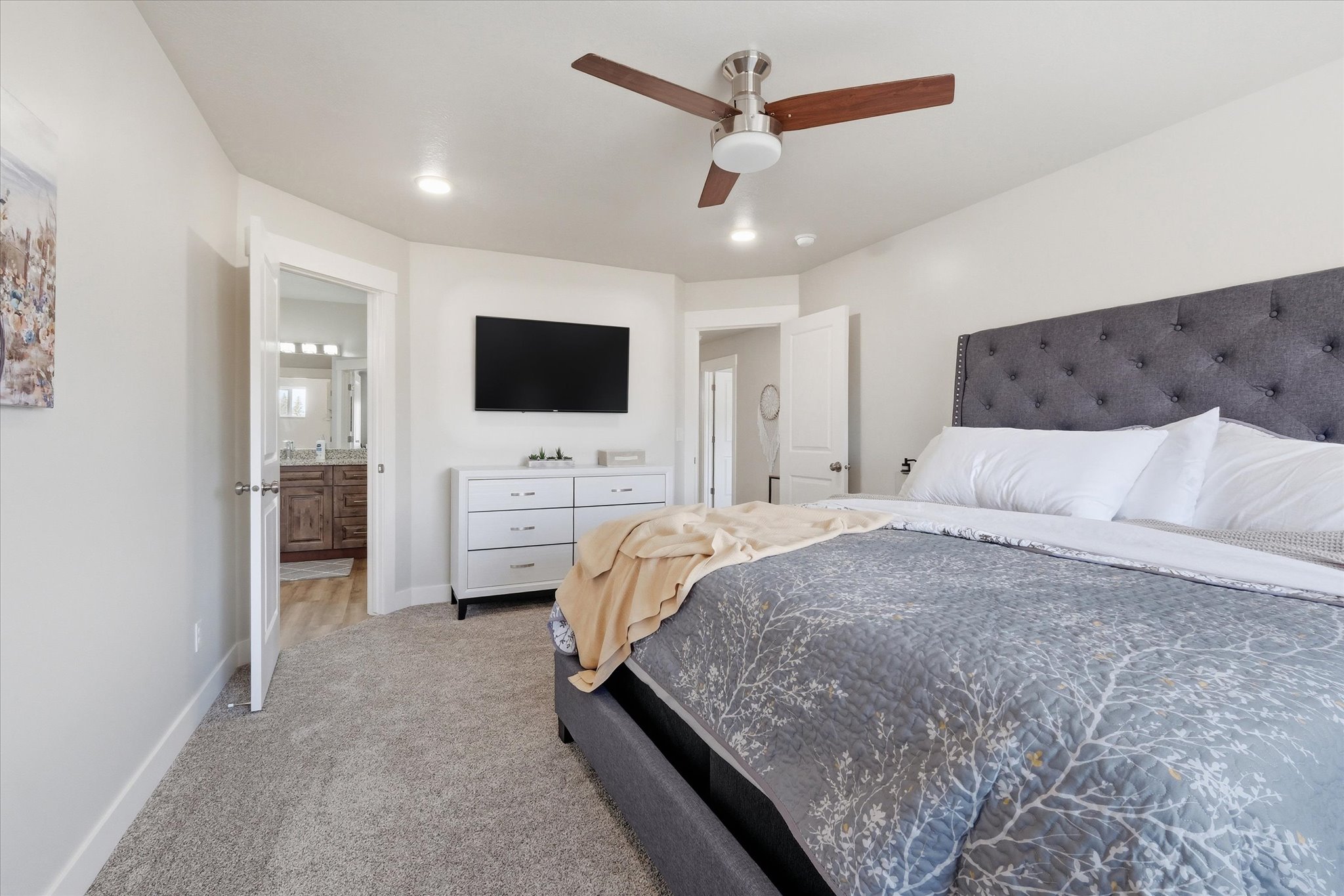 Bedroom with light carpet, connected bathroom, and ceiling fan