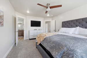 Bedroom with light carpet, connected bathroom, and ceiling fan