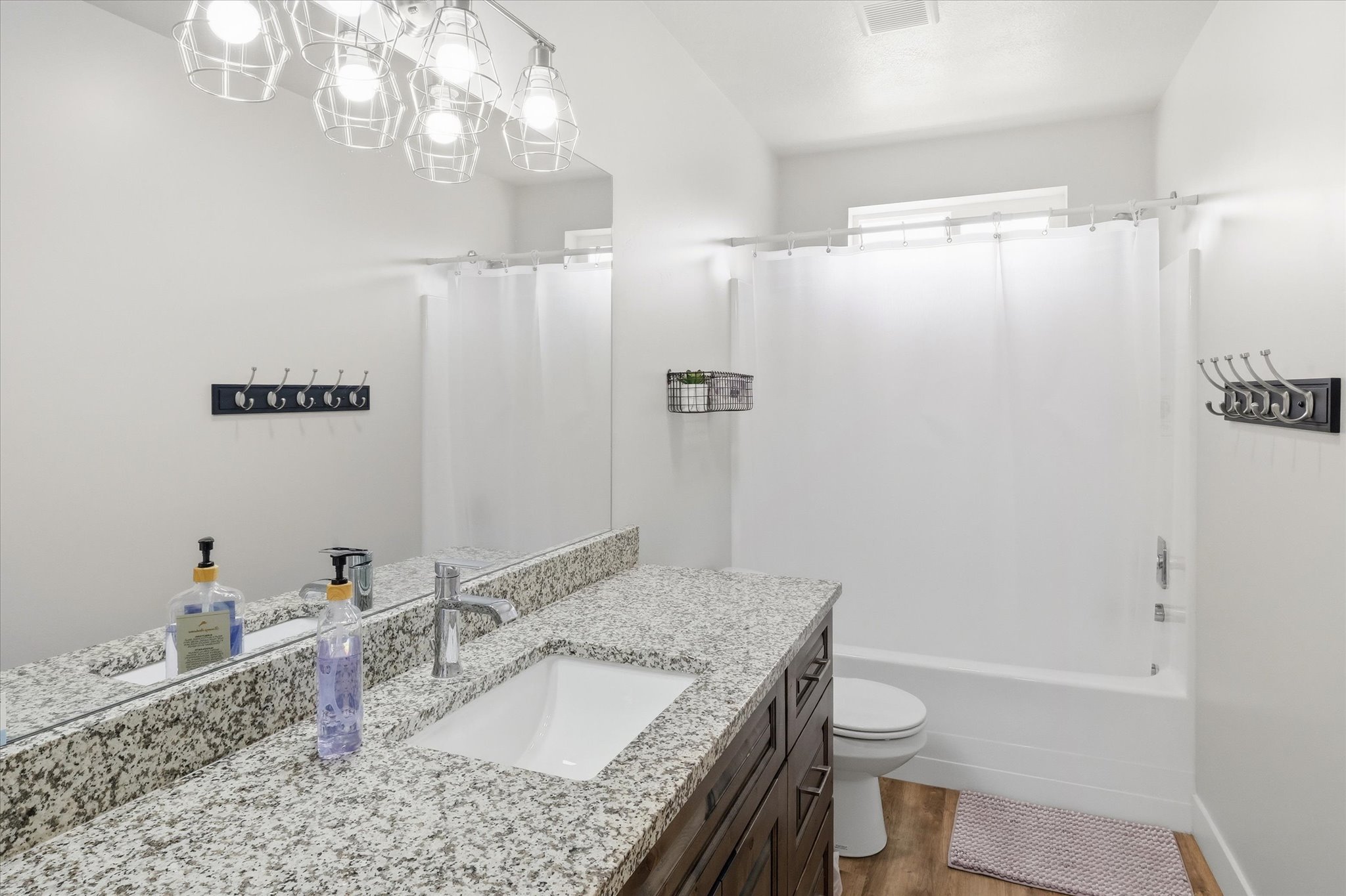 Full bathroom featuring vanity, light wood-type flooring, shower / bath combo, and hanging lights