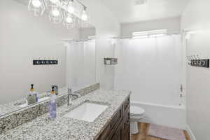 Full bathroom featuring vanity, light wood-type flooring, shower / bath combo, and hanging lights
