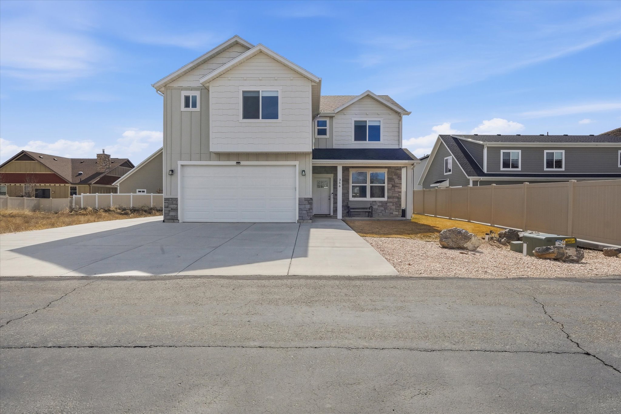 View of front of property featuring stone siding, a garage, board and batten siding, and driveway