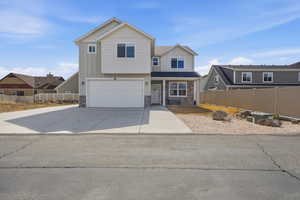 View of front of property featuring stone siding, a garage, board and batten siding, and driveway