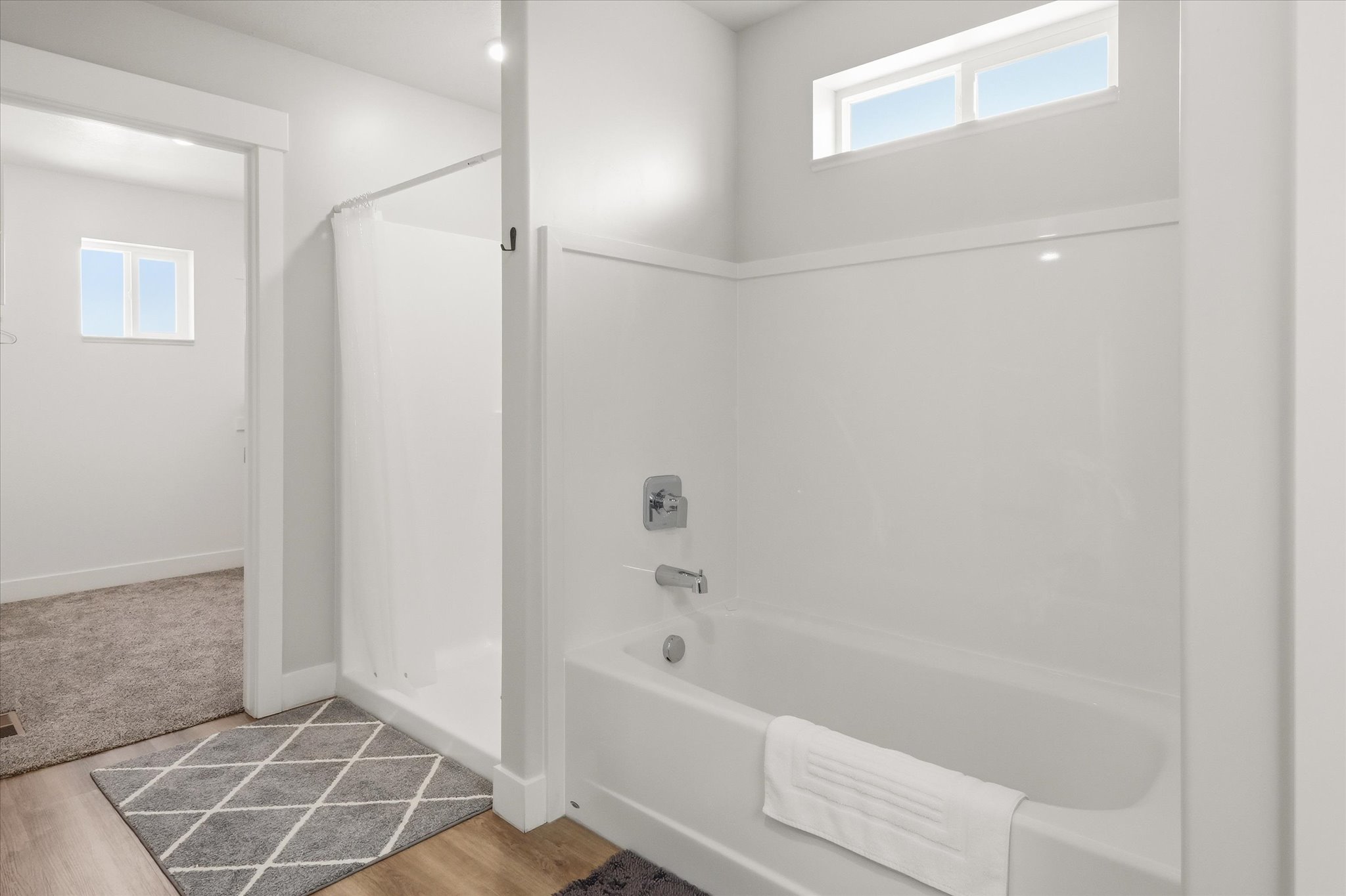 Bathroom featuring healthy amount of natural light, a stall shower, light wood-style flooring, and a bath