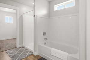 Bathroom featuring healthy amount of natural light, a stall shower, light wood-style flooring, and a bath