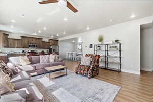 Living area with a ceiling fan, light wood-style floors, and recessed lighting