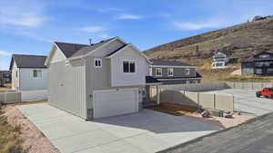 View of front of house with a garage, stone siding, driveway, and a residential view