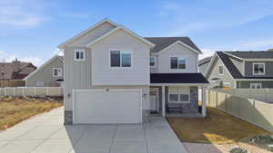 Traditional-style house with stone siding, covered porch, a garage, concrete driveway, and board and batten siding