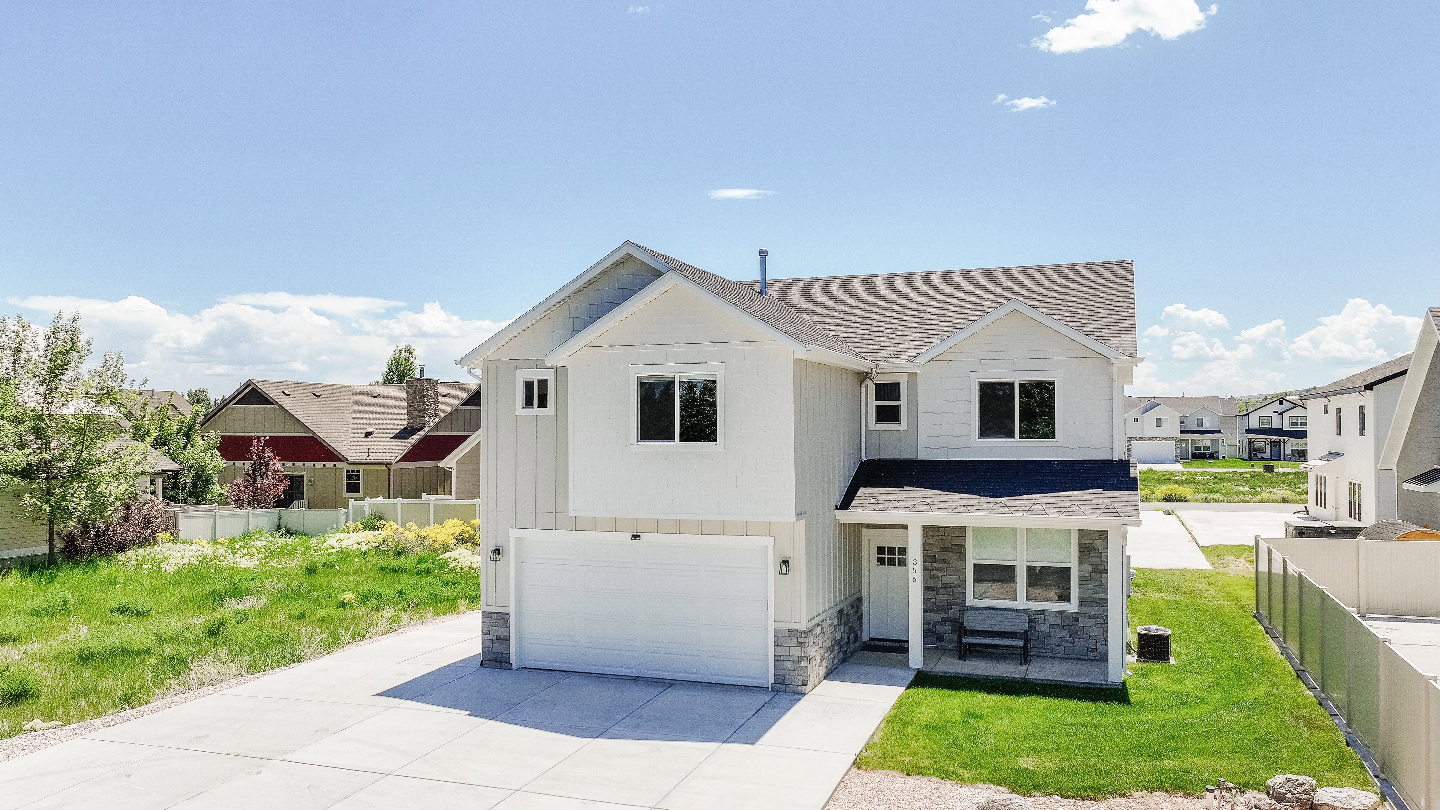View of front of house with stone siding, an attached garage, a shingled roof, and concrete driveway