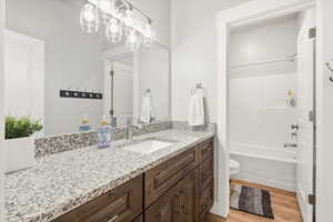 Bathroom with vanity, light wood-type flooring, and tub / shower combination
