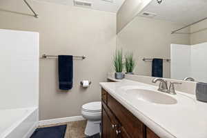 Bathroom featuring vanity, a textured ceiling, shower / bath combination, and light tile patterned floors