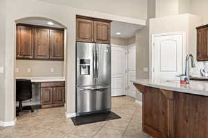 Kitchen featuring stainless steel fridge, built in study area, light tile patterned flooring, tasteful backsplash, and recessed lighting