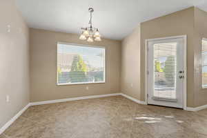 Unfurnished room with a chandelier, plenty of natural light, and a textured ceiling