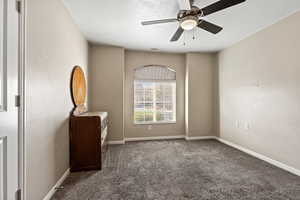 Empty room featuring ceiling fan, dark carpet, and a textured ceiling