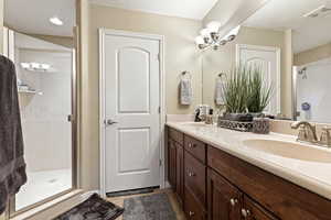 Bathroom featuring a shower stall, double vanity, hanging lights, and a textured ceiling