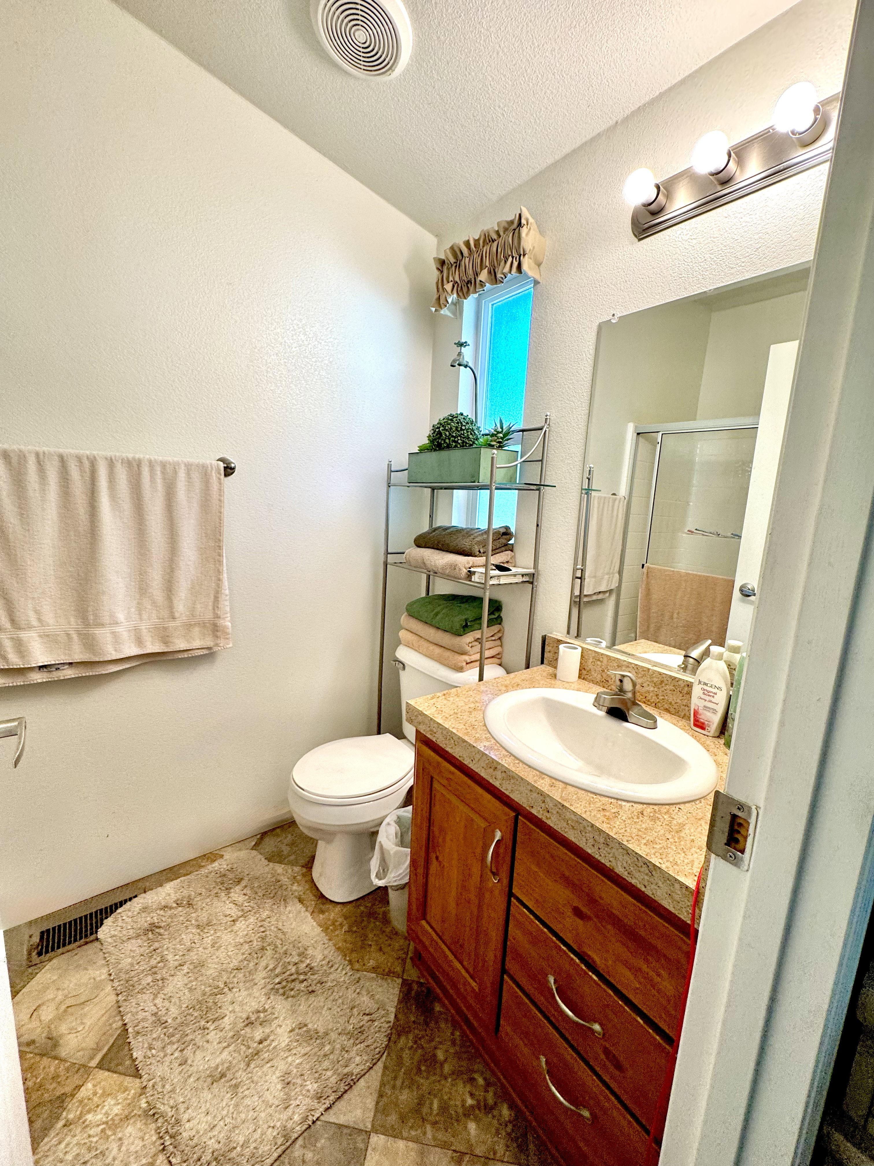 Bathroom featuring a stall shower, vanity, a textured ceiling, and a textured wall
