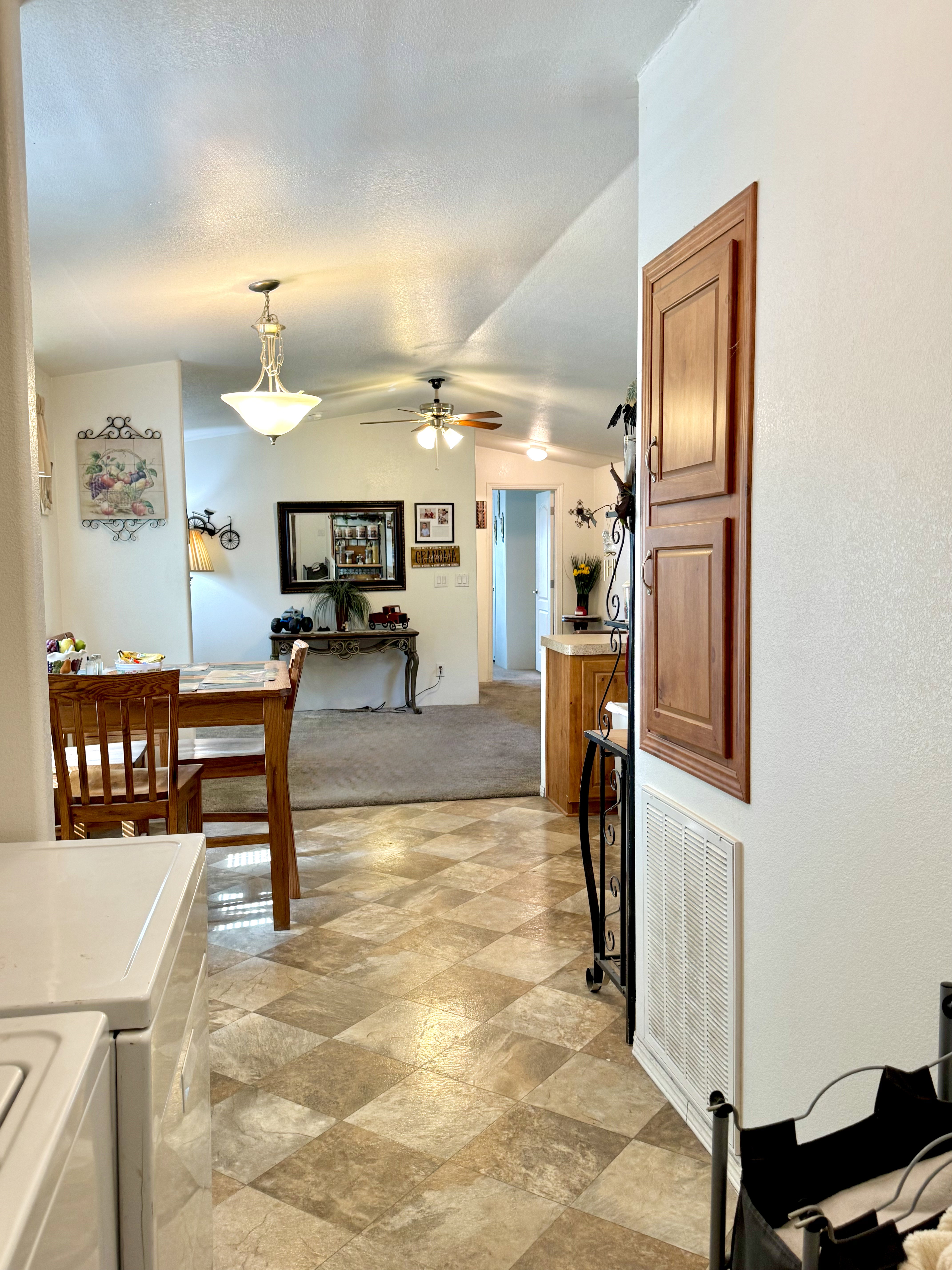 Dining area with ceiling fan, vaulted ceiling, stone finish floors, and washing machine and clothes dryer