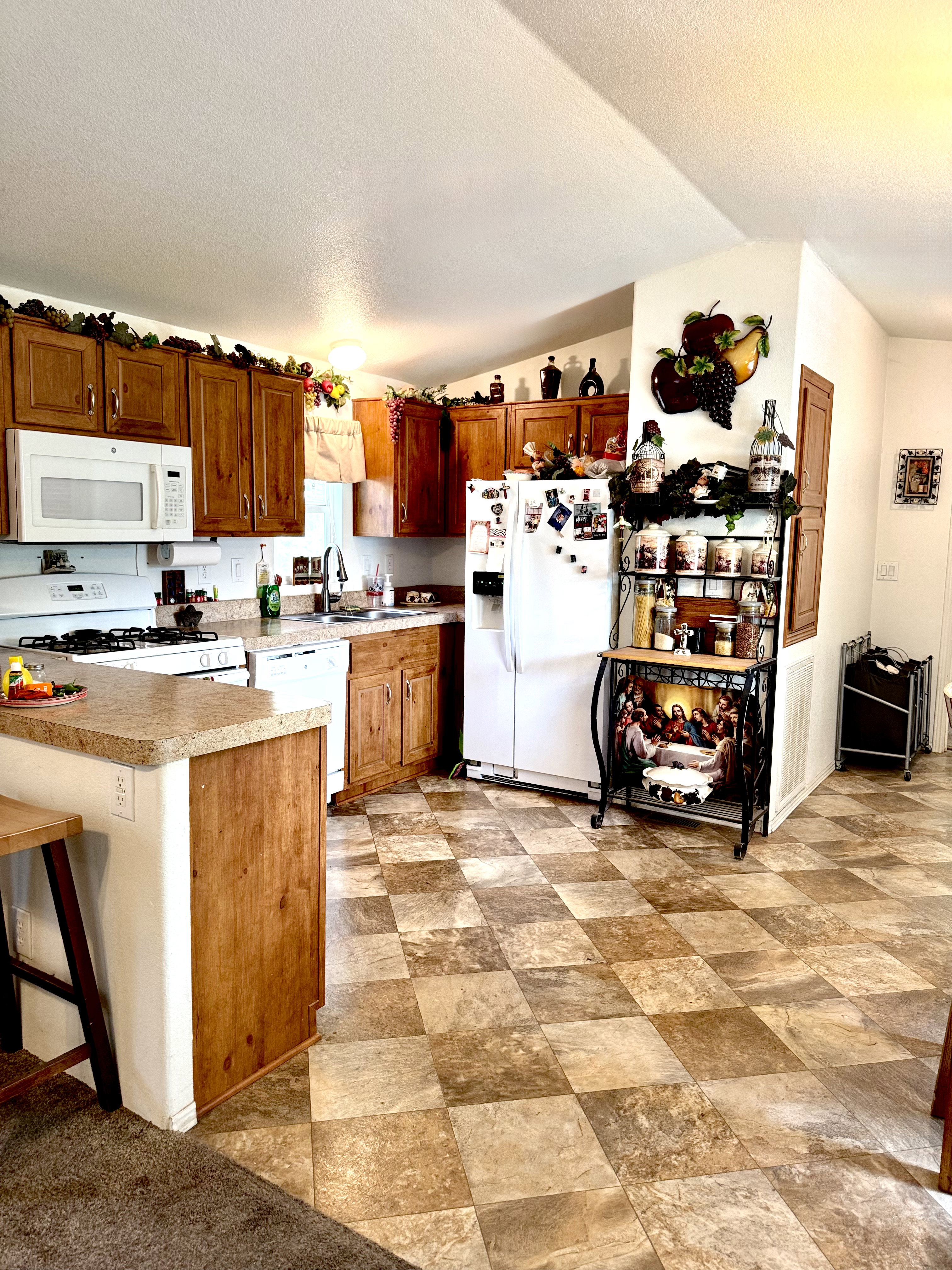 Kitchen featuring wood finish cabinetry, white appliances, light countertops, a kitchen breakfast bar, and stone finish flooring