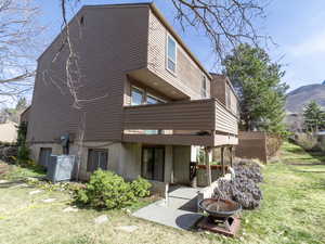 Rear view of house with a fire pit, a lawn, a mountain view, a patio, and a balcony