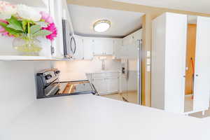 Kitchen featuring white cabinetry, stainless steel appliances, and light countertops