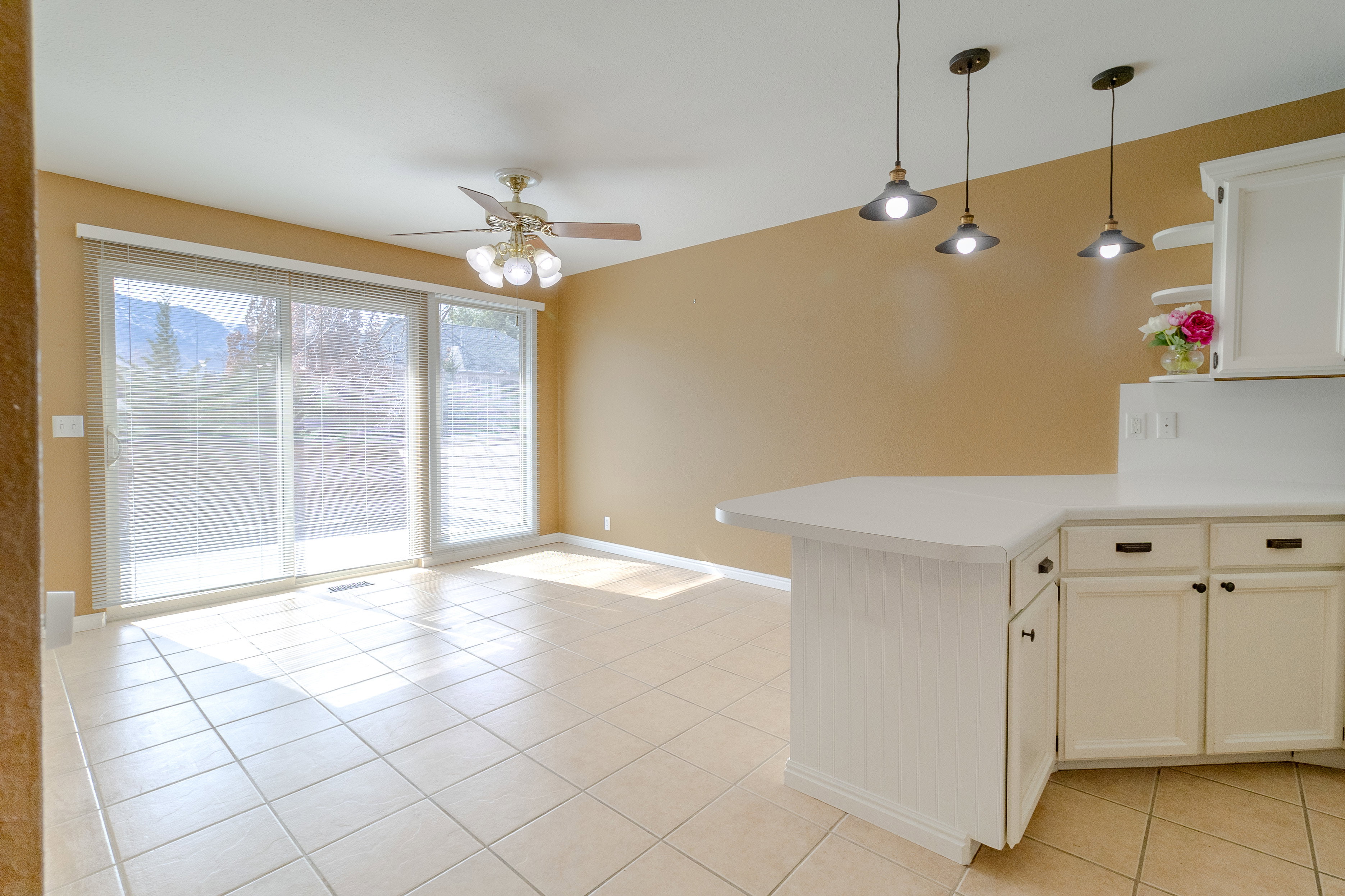 Kitchen featuring light countertops, a peninsula, decorative light fixtures, white cabinets, and ceiling fan