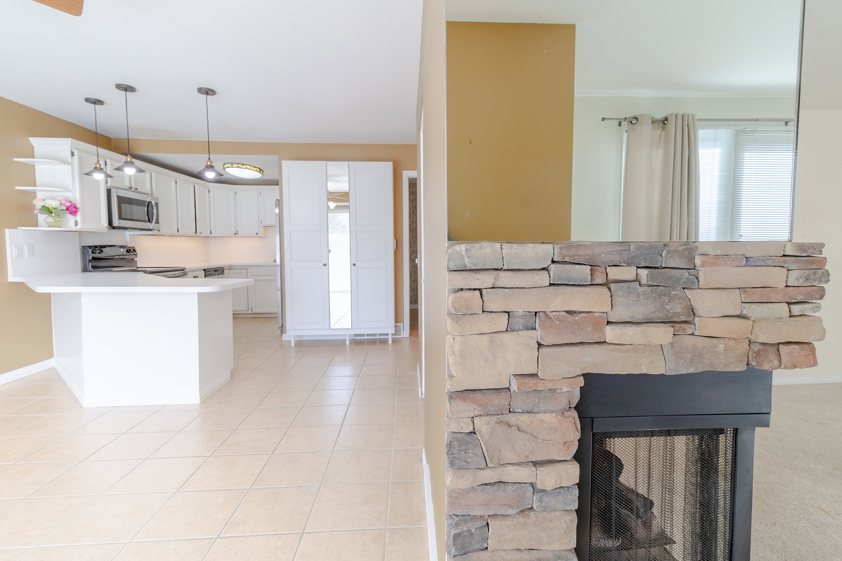 Kitchen featuring light countertops, stainless steel appliances, a peninsula, white cabinetry, and hanging light fixtures