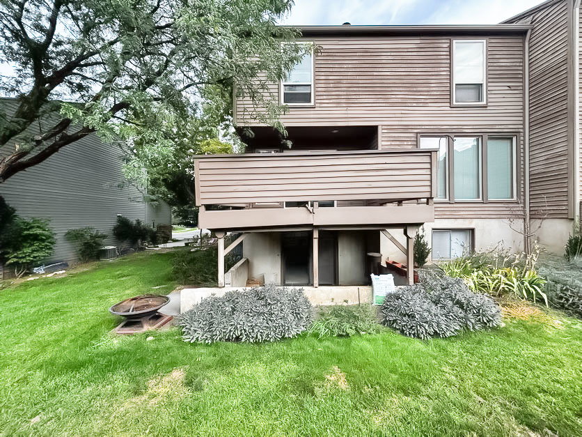 Back of house with a lawn, a fire pit, and a balcony