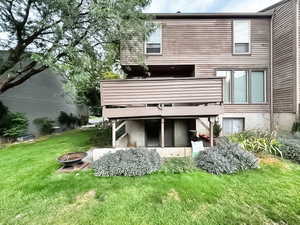 Back of house with a lawn, a fire pit, and a balcony