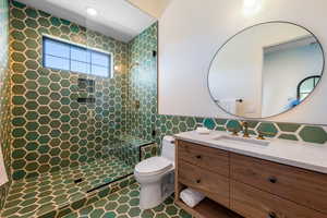 Bathroom with tile walls, walk in shower, and vanity