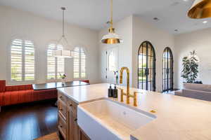 Kitchen featuring open floor plan, hanging light fixtures, dark wood finished floors, and light stone countertops