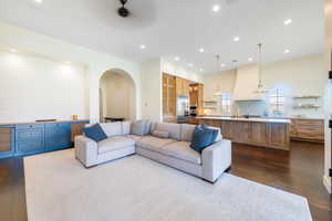 Living area with dark wood-style floors, arched walkways, and recessed lighting