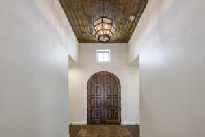 Foyer featuring arched walkways, a vaulted wooden ceiling, and dark wood-type flooring