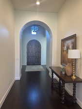 Entryway featuring arched walkways, dark wood finished floors, and a high ceiling