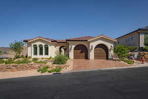 Mediterranean / spanish house with stucco siding, driveway, a tiled roof, and a garage