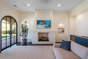 Living room featuring a fireplace, built in shelves, recessed lighting, french doors, and wood finished floors