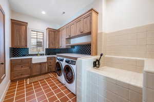Laundry area featuring washer and clothes dryer, light tile patterned flooring, and cabinet space