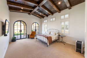 Bedroom with multiple windows, light carpet, french doors, access to exterior, and a high wood beamed ceiling