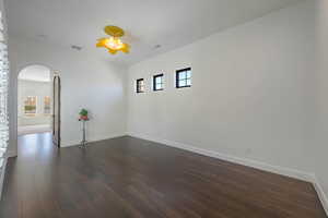 Unfurnished room with arched walkways and dark wood-type flooring