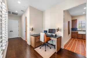 Office space with dark wood finished floors, arched walkways, and recessed lighting