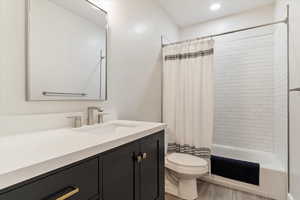 Bathroom featuring vanity, shower / bath combination with curtain, light wood finished floors, and recessed lighting