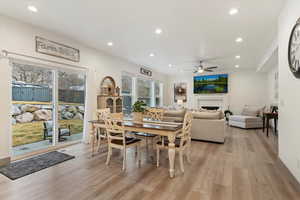 Dining space with light wood-style flooring, recessed lighting, a fireplace, and a ceiling fan