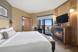 Bedroom featuring a glass covered fireplace and access to exterior