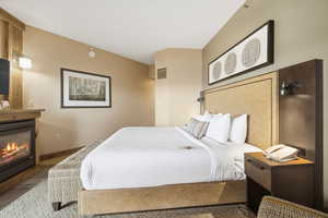 Bedroom with a glass covered fireplace and baseboards