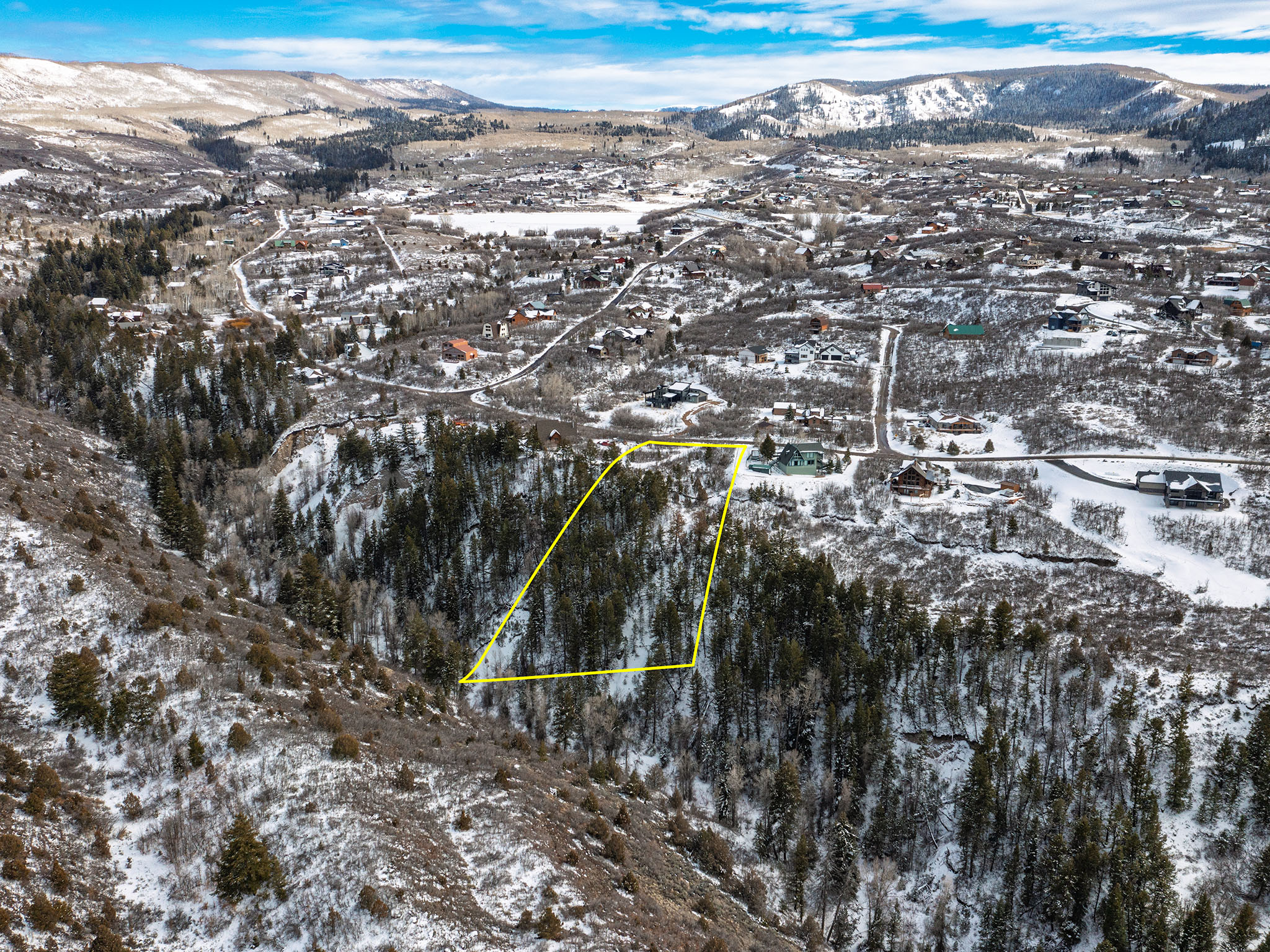 Snowy aerial view featuring a mountain view and property parcel outlined