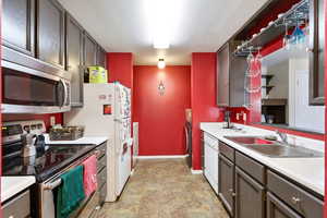 Kitchen featuring stainless steel appliances, light countertops, stone finish flooring, and dark wood finish cabinetry
